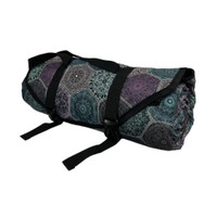 A rolled-up picnic rug in dark purple and teal patterns, secured with straps