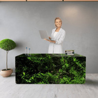 A fitted table cover featuring a green plant design, with a woman holding a laptop standing behind it.