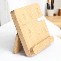 Wooden phone stand with wireless charging feature on a white surface.