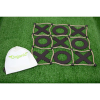 A Tic Tac Toe game with a black grid and wooden pieces, accompanied by a small white, branded bag, set on green grass.