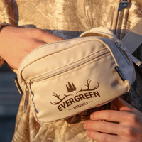 A light beige bum bag with a logo, featuring multiple zippered compartments and an adjustable strap.