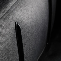 A close-up of fabric showing a textured black surface with a black trim detail. The material appears durable and structured.