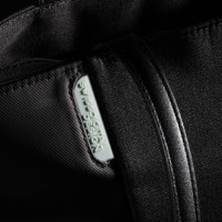 A black tote bag with a zipper and a prominent logo tag features a sleek, minimalist design.