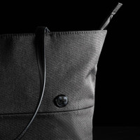 A black tote bag with a structured design and a sleek shoulder strap, featuring a circular logo.