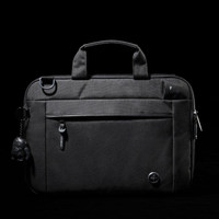 A black laptop sleeve with a zippered front pocket, handle, and a keychain accessory. It features a logo.