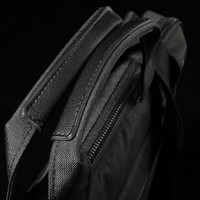 A black laptop sleeve with textured fabric and zipped closure, featuring sturdy handles for carrying.