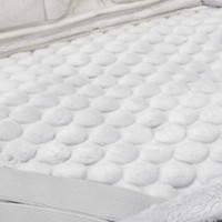 A soft, textured surface featuring white fluffy material with raised round patterns.