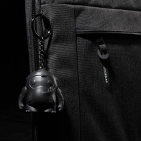 A black laptop sleeve features a textured surface and a keychain with a small black character.