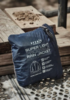 A navy blue packable rain jacket neatly folded and zipped, featuring a logo and information on the packaging.