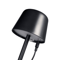 A black mini rechargeable lamp with a curved top and charging cable attached. It features a clean, modern design.