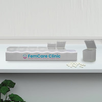 A white weekly pill box with multiple compartments, some open, alongside white pills and a plant. It has a logo.