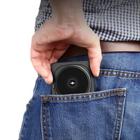 A compact black wireless charger is being pulled from a back pocket of blue jeans.