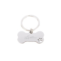 A metallic dog bone keytag with a keyring, featuring a logo and a paw print design.