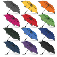 A collection of BLUNT Metro Umbrellas in various colours, including grey, yellow, orange, pink, red, green, blue, black, and purple.