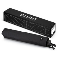 A black BLUNT Metro Umbrella laid flat next to its rectangular packaging, featuring a logo.