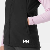 Close-up view of a black softshell vest showcasing a zippered side pocket, streamlined design, and Helly Hansen (HH) logo near the hem.