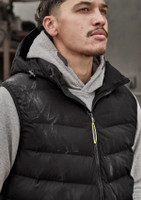 A unisex black hooded puffer vest is worn over a grey hoodie. The vest features a logo and a zip closure.