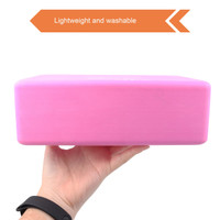 A pink EVA yoga block held in a hand, featuring a smooth surface and lightweight design.