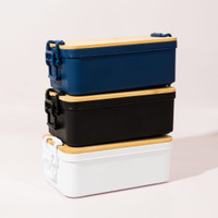 Three stacked lunch boxes in navy blue, black, and white, each with a wooden lid and a branded logo.