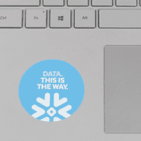 A round laptop sticker in light blue with a snowflake design and white text.