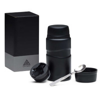 A drink bottle in matte black with a removable lid, inner container, and a metal spoon, placed beside a box.