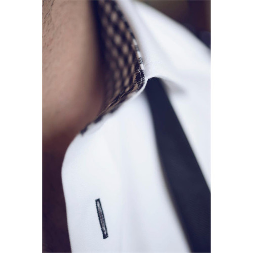 A close-up of a men's shirt featuring a white fabric with a checkered collar and black detailing. It has a logo on the collar. A close-up of a men's shirt featuring a white fabric with a checkered collar and black detailing. It has a logo on the collar.
