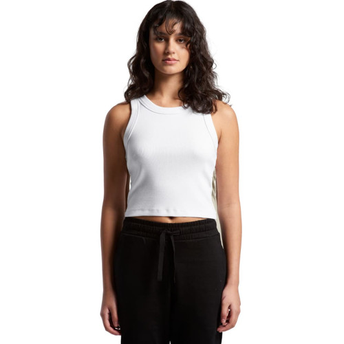 A woman wearing a white organic rib crop tank top, styled with black pants, standing against a plain background. A woman wearing a white organic rib crop tank top, styled with black pants, standing against a plain background.