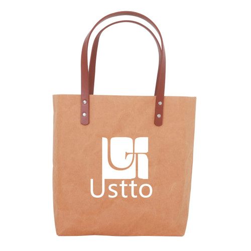 A washable kraft paper bag in tan with a brown PU handle and a logo. A washable kraft paper bag in tan with a brown PU handle and a logo.