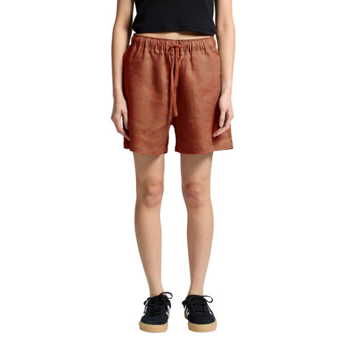 Linen dress shorts in a terracotta colour featuring an elastic waistband and side pockets, shown on a model.