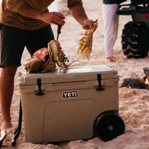 Man preparing lobster on YETI cooler at beach campfire.