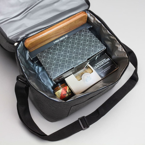 A cooler bag in grey containing a cheese set, jar, and assorted snacks. The interior is lined with silver material.