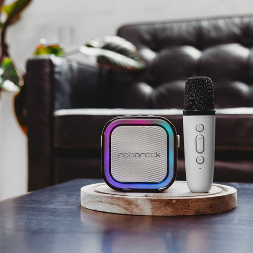 A portable karaoke machine in black and silver with a multi-coloured speaker design, accompanied by a silver microphone.