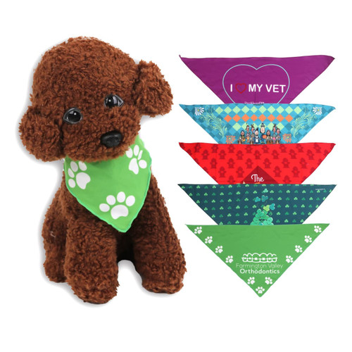 A plush brown dog wearing a green triangle pet bandana, surrounded by various colourful bandanas featuring different designs.