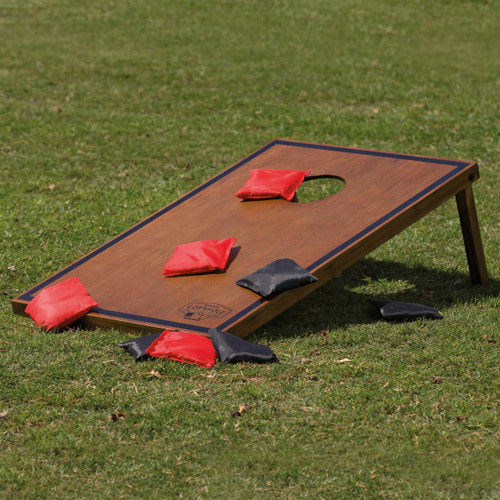 A Backyard Cornhole Set featuring a wooden board and red and black bean bags, placed on grass. A Backyard Cornhole Set featuring a wooden board and red and black bean bags, placed on grass.