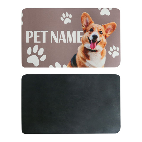A pet feeding mat with a smiling dog illustration and paw prints, featuring a textured black reverse side.