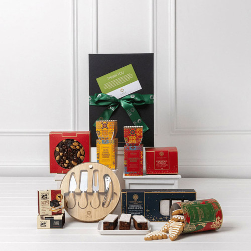 A gift pack featuring festive snacks, assorted chocolates, utensils, and decorative packaging in red, gold, and green.