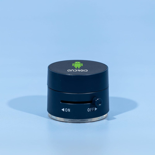 A black and silver device with a logo on top and a dial on the side, resting on a blue background.