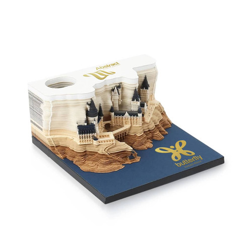 A 3D paper carving notepad in cream and blue featuring an intricate castle design atop a layered landscape.