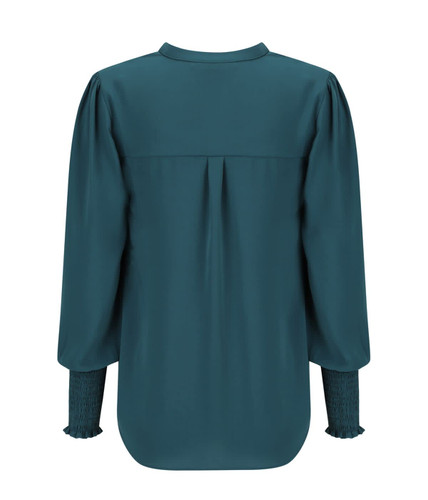 A long sleeve top in deep teal with gathered sleeves and a pleat detail at the back, featuring a branding logo.