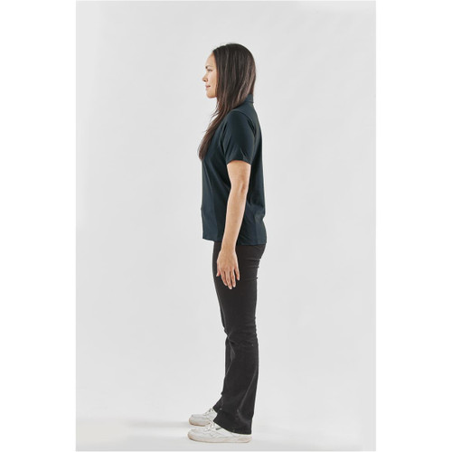 A side view of a woman wearing a black women's polo shirt and black pants, with a logo on the shirt.