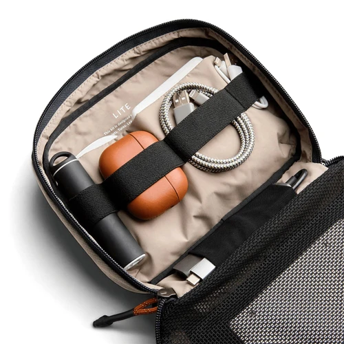 A tech kit featuring a grey exterior, tan interior, drink bottle, earphones, charging cables, and a pen.