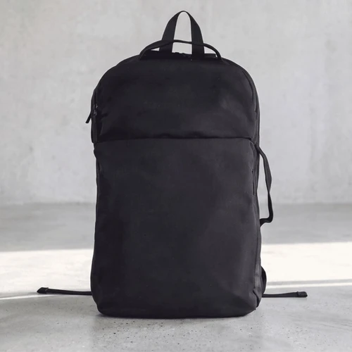 A black backpack with a sleek design and a front pocket, featuring straps and a logo on the side.