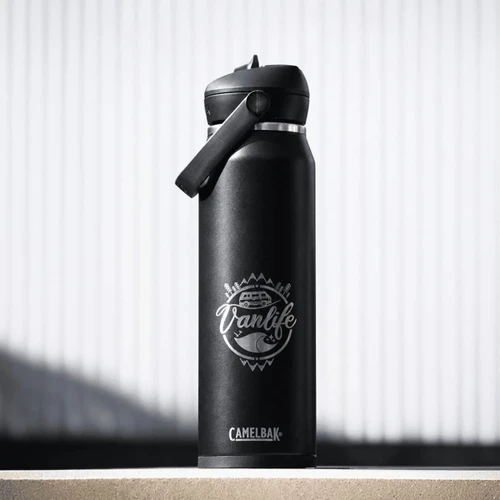 A drink bottle in matte black with a flip straw lid and a logo featuring a vanlife theme.