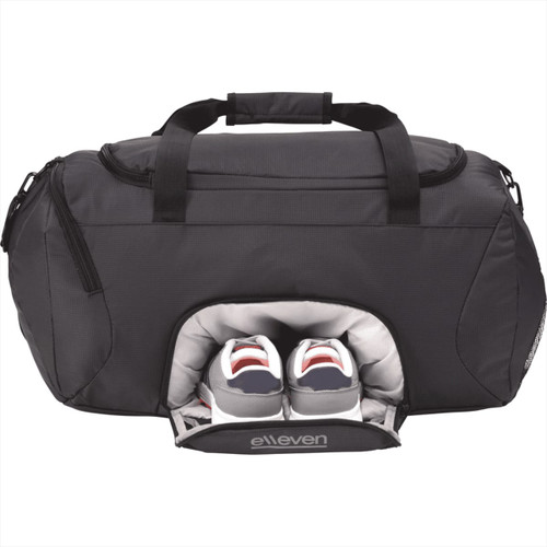 A black duffle bag featuring a separate compartment for shoes, with two pairs of shoes visible. The bag has a logo. A black duffle bag featuring a separate compartment for shoes, with two pairs of shoes visible. The bag has a logo.