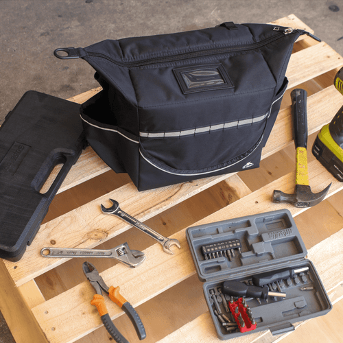 A black cooler bag with a reflective stripe, surrounded by tools on a wooden pallet. It features a logo on the front. A black cooler bag with a reflective stripe, surrounded by tools on a wooden pallet. It features a logo on the front.