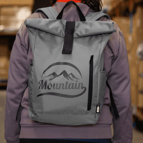 A grey roll-top backpack with a logo, featuring two side pockets and adjustable straps.