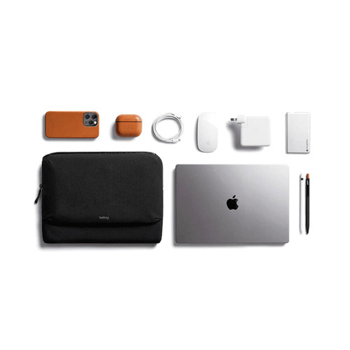 A black laptop caddy with a silver laptop, accessories in orange and white including a phone, mouse, and charger. A black laptop caddy with a silver laptop, accessories in orange and white including a phone, mouse, and charger.