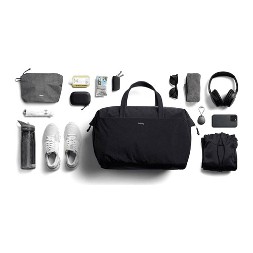 A black duffel bag surrounded by a water bottle, shoes, a hoodie, headphones, sunglasses, and various accessories. A black duffel bag surrounded by a water bottle, shoes, a hoodie, headphones, sunglasses, and various accessories.