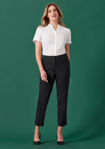 A mid-waist slim leg pant in black, paired with a white short-sleeve shirt. The model poses against a green background. A mid-waist slim leg pant in black, paired with a white short-sleeve shirt. The model poses against a green background.