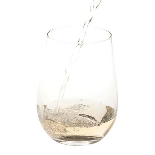 A clear stemless wine glass with a pour of liquid creating bubbles inside.